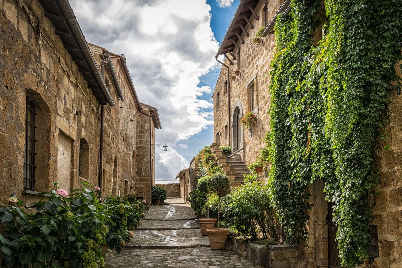 Stone houses, ivy and flowers along a lane in Pienza, Tuscany