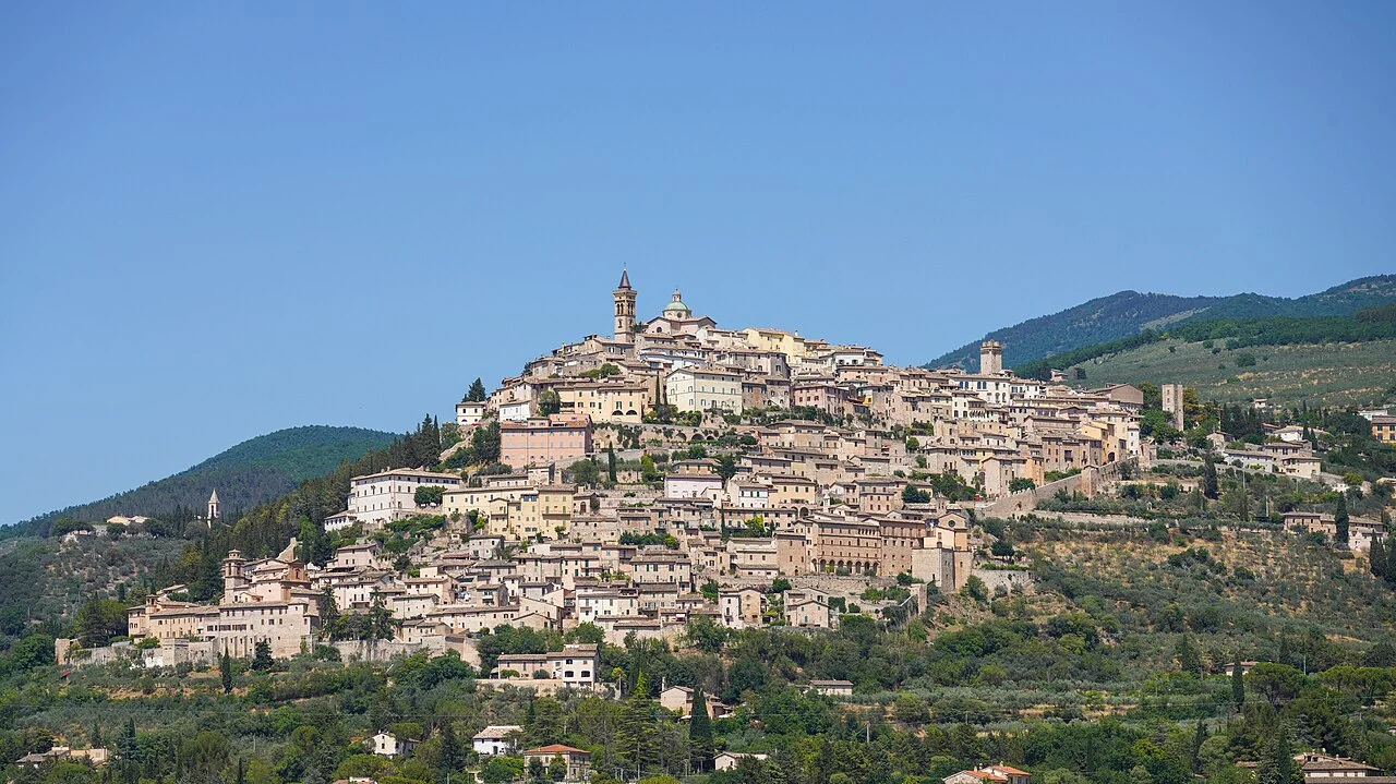 The compact hill town of Trevi above terraced olive slopes under a blue sky