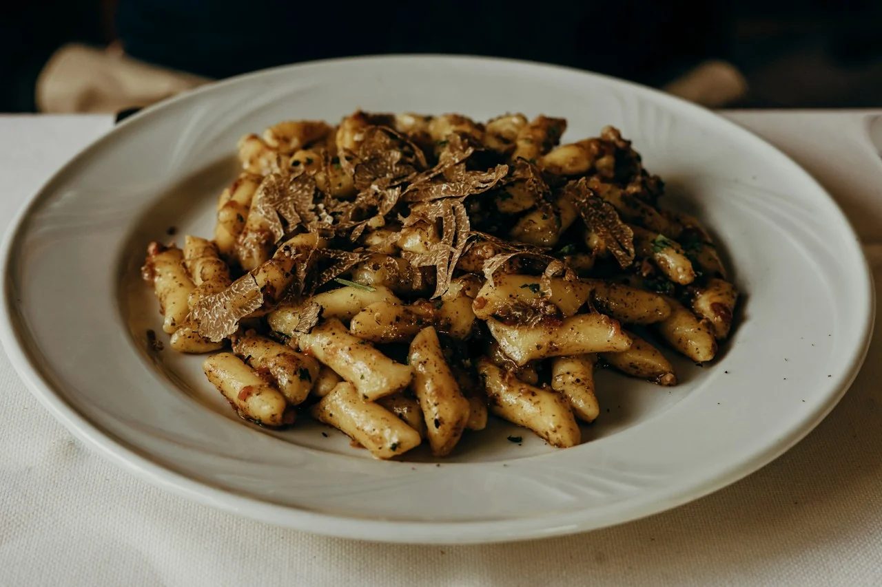 Gnocchi with sausage ragu and shaved black truffle on a white plate